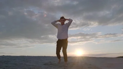 Dancer performs a freestyle dance composition on the sandy beach at sunset Stock Footage 135610877