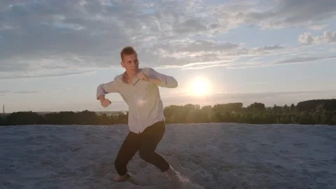 Dancer performs a freestyle dance composition on the sandy beach at sunset Stock Footage 135611210