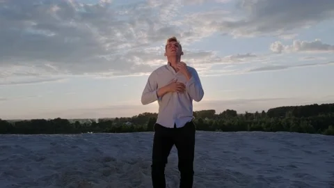 Dancer performs a freestyle dance composition on the sandy beach at sunset Stock Footage 135611256
