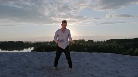 Dancer performs a freestyle dance composition on the sandy beach at sunset Stock Footage 135611264