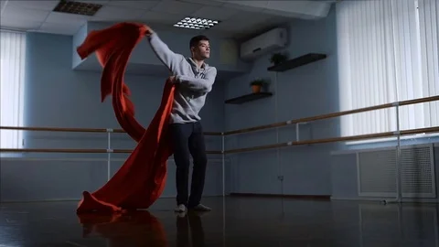 Dancer performs his emotional dance using a large red cloth in a large studio Stock Footage 70366598