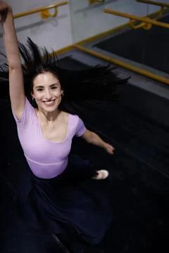 Dancer performs a joyful leap in a ballet studio with mirrors and wooden floors Stock Photos