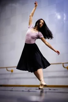 Dancer performs a routine in a dance studio with wooden floor and mirrors Stock Photos