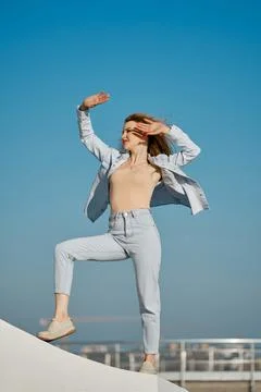 Dancer poses confidently against a clear blue sky at a vibrant outdoor locati Foto stock