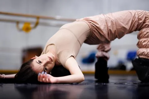 Dancer practices a stretch on the floor at a dance studio during a training Stock Photos