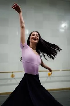 Dancer practices at a studio during a dance class while wearing a pink top and Stock Photos