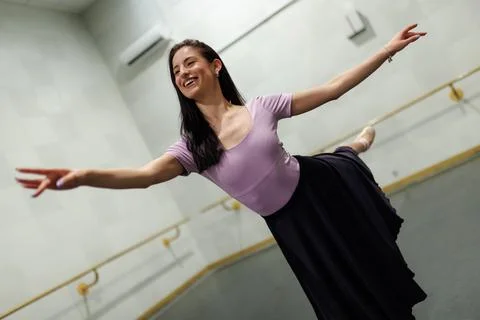 Dancer practices in a studio while wearing a pink top and black skirt during a Stock Photos