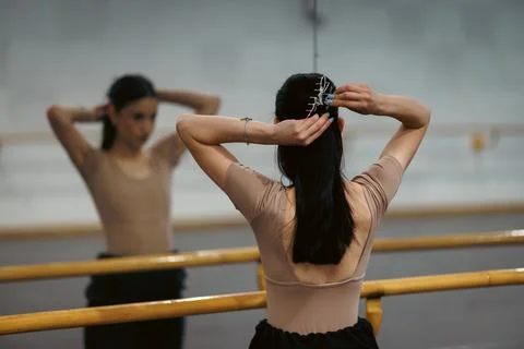 Dancer prepares in front of mirror at ballet studio in the evening for practice Stock Photos