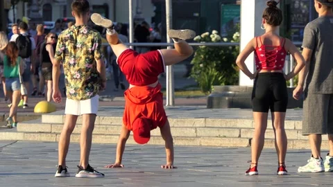 A dancer in a red outfit performs acrobatic stunts, standing on his hands. Stock Footage 134465862