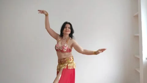 A dancer in a red suit is dancing an oriental dance on a white background. A Stock Footage 267707748