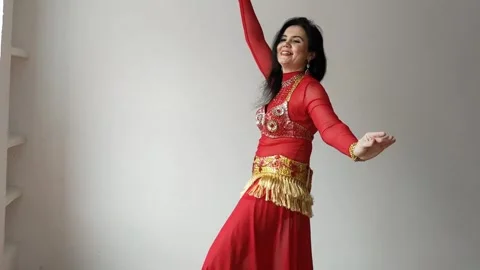 A dancer in a red suit is dancing an oriental dance on a white background. A Stock Footage 269287465
