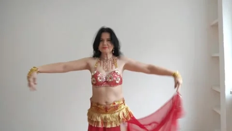 A dancer in a red suit is dancing an oriental dance on a white background. A Stock Footage 273671655