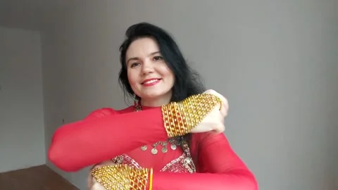 A dancer in a red suit is dancing an oriental dance on a white background. A Stock Footage 275225248