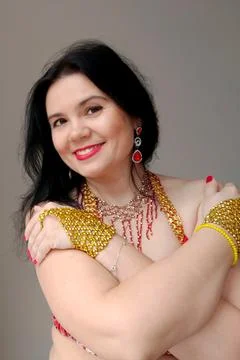 A dancer in a red suit is dancing an oriental dance on a white background. A Stock Photos