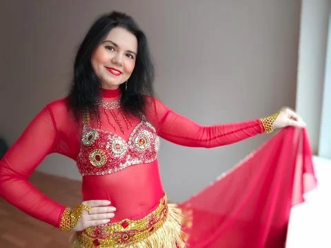 A dancer in a red suit is dancing an oriental dance on a white background. A Stock Photos