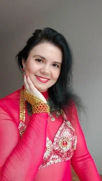 A dancer in a red suit is dancing an oriental dance on a white background. A Foto stock