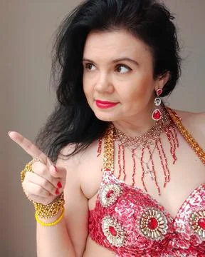 A dancer in a red suit is dancing an oriental dance on a white background. A Stock Photos