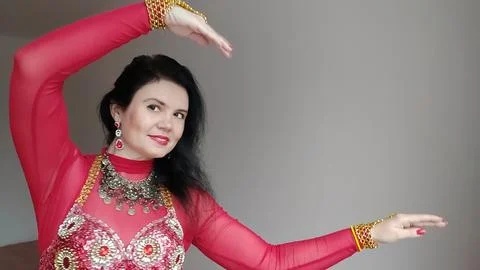 A dancer in a red suit is dancing an oriental dance on a white background Stock Photos