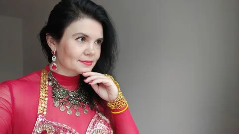 A dancer in a red suit is dancing an oriental dance on a white background. Free Foto stock
