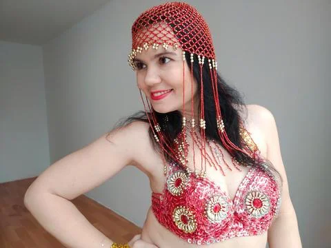 A dancer in a red suit is dancing an oriental dance on a white background. Free Stock Photos