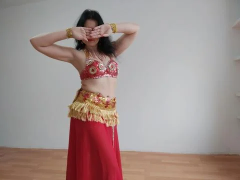 A dancer in a red suit is dancing an oriental dance on a white background. Free Stock Photos