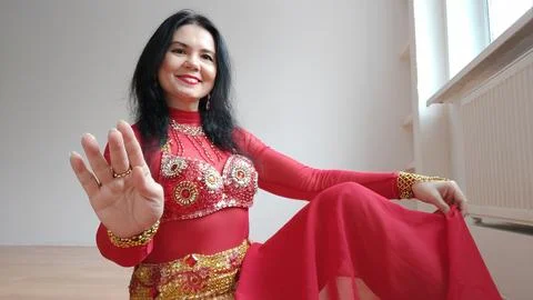 A dancer in a red suit is dancing an oriental dance on a white background. Free Foto stock