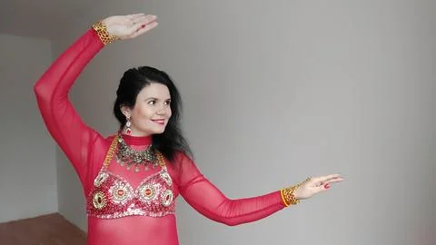 A dancer in a red suit is dancing an oriental dance on a white background Foto stock