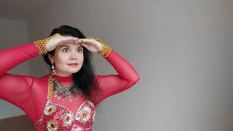 A dancer in a red suit is dancing an oriental dance on a white background Stock Photos