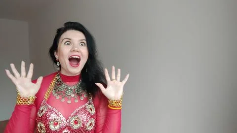 A dancer in a red suit is dancing an oriental dance on a white background Stock Photos