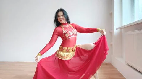 A dancer in a red suit is dancing an oriental dance on a white background. Free Stock Photos