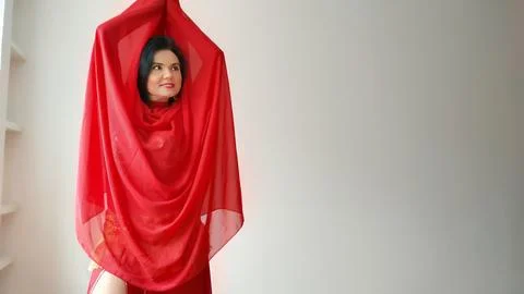 A dancer in a red suit is dancing with a red shawl an oriental dance on a white Foto stock