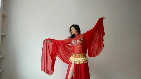 A dancer in a red suit is dancing with a red shawl an oriental dance on a white Foto stock
