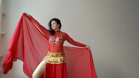 A dancer in a red suit is dancing with a red shawl an oriental dance on a white Foto stock