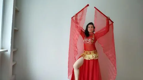 A dancer in a red suit is dancing with a red wings an oriental dance on a white Stock Photos