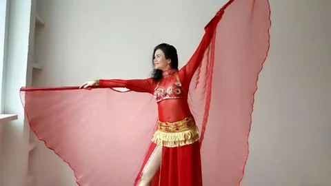 A dancer in a red suit is dancing with a red wings an oriental dance on a white Stock Photos