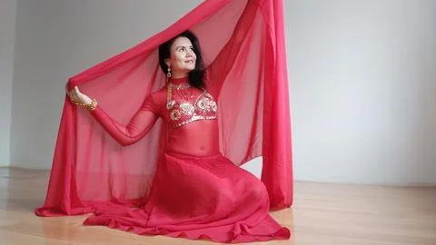 A dancer in a red suit is dancing with a red shawl an oriental dance on a white Stock Photos