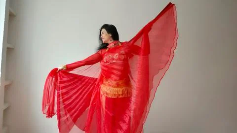 A dancer in a red suit is dancing with a red wings an oriental dance on a white Foto stock