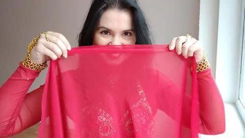 A dancer in a red suit is dancing with a red shawl an oriental dance on a white Foto stock
