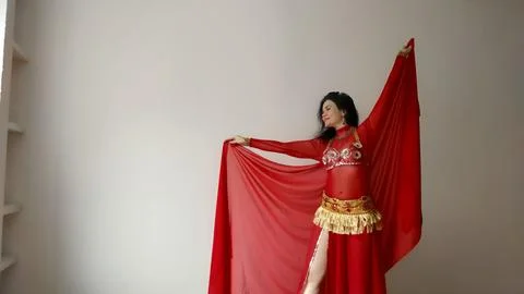A dancer in a red suit is dancing with a red shawl an oriental dance on a white Stock Photos