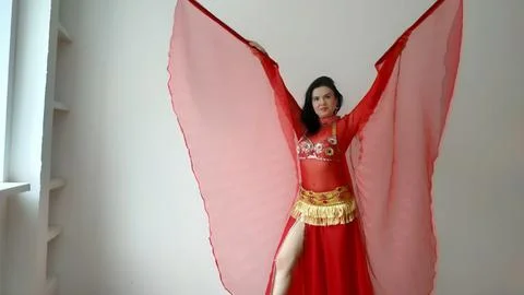A dancer in a red suit is dancing with a red wings an oriental dance on a white Stock Photos