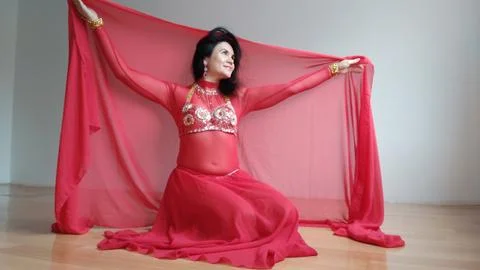 A dancer in a red suit is dancing with a red shawl an oriental dance on a white Stock Photos