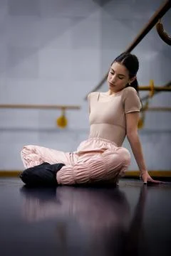 Dancer rests on the floor in a dance studio during practice while wearing a Stock Photos