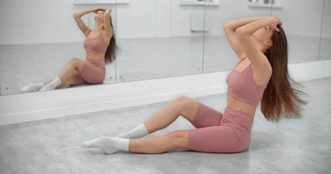 Dancer is sitting on the floor and warming up in front of the mirror wall in the Stock Footage 145953727