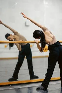 Dancer stretches and practices in a studio with large mirrors during a training Stock Photos