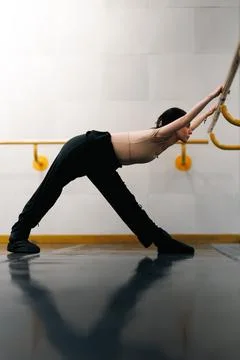 Dancer stretching at the ballet bar in a studio during a morning class in a Stock Photos