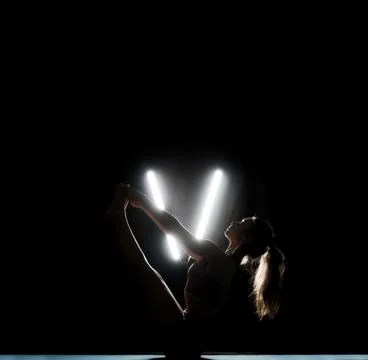 A dancer is in a strong pose in a dark studio. Bright lights create a V shape Stock Photos