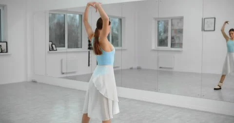 Dancer warms up infromt of the mirror wall in the white bright dance hall before Video stock 144570397