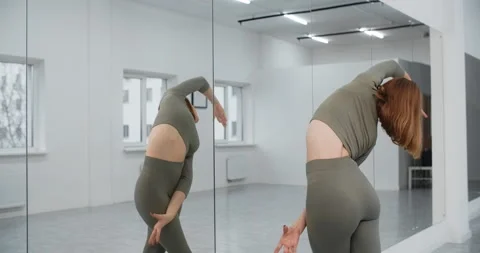 Dancer warms infront of the mirror wall at the white bright dance hall, ballet Stock Footage 147385344