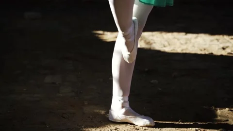 Dancer in white tights and pointe shoes stands on the ground Stock Footage 170361064