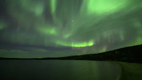 Dancing aurora over sandy lake coast Stock Footage 250292788